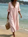 Nahaufnahme eines rosa V-Ausschnitt Urlaubskleides mit feinem Spitzenbesatz am Strand - Rosa