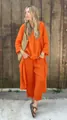Full-length outdoor shot of a woman in a bright orange loose linen two-piece set - S / Top And Bottom / Orange Red