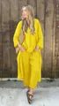 Detail view of woman wearing yellow linen two-piece shirt and pants set outdoors - S / Top And Bottom / Yellow
