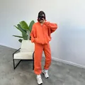 Oversized orange fleece zip-up hoodie and joggers set for women in minimalist setting - Orange Red