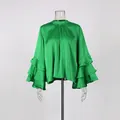 Detailed macro view of elegant green satin blouse featuring multi-layered ruffled bell sleeves - Green
