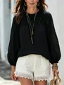 Detailansicht der schwarzen Bluse mit Laternenärmeln und weißen Shorts mit Spitzenbesatz. - S / Oberteile / Schwarz