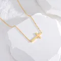 Detailed view of a minimalist gold stainless steel cross necklace on white stones - Gold