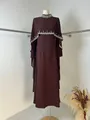 Detail view of burgundy long dress featuring an elegant rhinestone beaded cape overlay. - Coffee