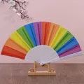 Detailed view of a 23cm vibrant rainbow Spanish folding fan displayed on a wooden stand. - 600 Pieces/Pack / Rainbow Vertical Stripes
