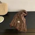 Detailed macro view of brown wrinkled cotton-linen scarf featuring delicate fringed edges - Coffee
