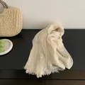 Detail view showing the pleated texture and fringed edges of a cream cotton-linen scarf. - Beige