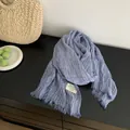 Detail view of the soft pleated texture and tassel edges of the blue cotton linen scarf. - Blue