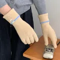 Detailed view of cream knitted gloves with light blue trim and circular patch - One Size / Beige