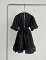 Detalle de vestido negro de capas con cuello en V, mangas abullonadas y pedrería. - S / Vestidos / Negro