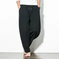 Detail view of men's loose black harem pants with drawstring waist and wide legs. - M / Bottoms / Black