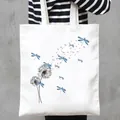 Close-up detail of a white canvas tote bag featuring a blue dragonfly and dandelion print - Blue Dragonfly and Dandelion Style (24)