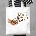Eco-friendly white canvas tote bag featuring a stylish monarch butterfly graphic print - Hands Releasing Butterfly Style (20)