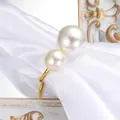Elegant gold napkin ring featuring two glossy faux pearls on a white satin cloth - Gold Pearl Style (C57) / Gold