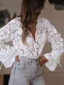 Close-up detail of white floral hollow-out lace shirt with flared sleeves and ties. - S / Tops / White