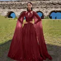 Elegant burgundy sequin mesh evening gown featuring dramatic floor-length cape sleeves - Burgundy