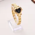 Close-up detail of an elegant gold heart-shaped quartz watch on a transparent stand - Gold/Black Dial (WT192)