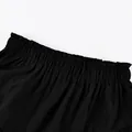 Close-up detail view of black high waist ruffled elastic waistband on tiered fashion skirt - S / Black