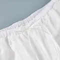 Close-up of elastic waistband with decorative white drawstring bow on sheer pants. - S / Bottoms / White Striped