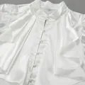 Detailed view of white satin ruffle shirt with elegant pearl buttons and stand collar - S / Tops / White