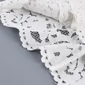 Gros plan sur un tissu de dentelle blanche délicate aux motifs de broderie fleuris. - S / Hauts / Blanc