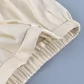 Close-up of elastic waistband on cream satin lantern trousers with smooth texture - S / Bottoms / Apricot