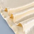 Detalle del dobladillo de la falda de satén champán con costuras finas y textura de seda suave - S / Bottoms / Champán