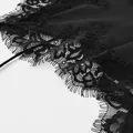 Gros plan sur la bordure en dentelle de cils noire sur un tissu en satin de soie lisse - S / Robes / Noir