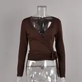 Detailed view of a brown long-sleeved V-neck wrap top for women on a clear mannequin. - S / Tops / Brown