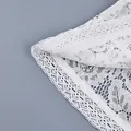 Primo piano della trama del pizzo bianco all'uncinetto di una camicia da donna. - Taglia S / Top / Bianco