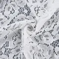 Vista macro di intricato tessuto di pizzo floreale bianco con delicata trama a rete. - Taglia S / Top / Bianco