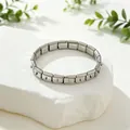 Detailed view of a silver stainless steel modular charm bracelet on a white rock. - Hook Polished / Silver