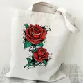 Durable white canvas tote bag featuring a vibrant red rose print with black splatters - Rose and Splatter (STD2097-J)