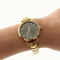 Dichtbij van een elegant goudkleurig dameshorloge met een grijze wijzerplaat om de pols - Gouden Numerieke Ronde Stijl (4678) / Goud Zwart