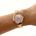 Detailopname van een elegant dameskwartshorloge met gouden stalen band en roze wijzerplaat. - Gouden Numerieke Ronde Stijl (4677) / Goud Roze