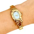 Close-up detail of unique golden fish-shaped fashion watch with a light blue dial on a wrist - 5463-Gold Green