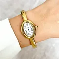 Detailed close-up of an elegant gold oval bangle watch featuring Roman numerals on a wrist - Oval Dial White Bangle Style / Gold
