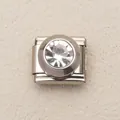 Dettaglio di un charm italiano in acciaio inossidabile con grande strass rotondo trasparente - Bianco
