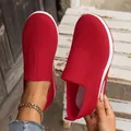 Close-up of red breathable knit slip-on sneakers for women shown on a rustic wooden background - 36 / Red