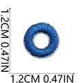 Close-up of small round blue embroidered patch showing 1.2cm diameter measurement detail - Letter O