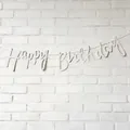 White script Happy Birthday banner for party decoration on white brick wall - Cursive Letter Style / White