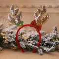 Close-up of golden glitter reindeer antler headband with a red bow and festive bell. - Gold Glitter Antler Headband