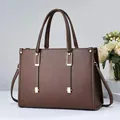 Vista frontal del bolso de cuero granulado marrón con elegantes detalles metálicos dorados - Café