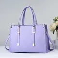 Elegante bolso de mano lavanda con textura de cuero y sofisticados toques dorados - Púrpura Taro