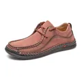 Detail view of men's brownish-red leather driving shoes with hand-stitched accents. - 38 / Red