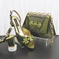 Dettaglio di sandali verdi con tacco alto in pelle di serpente e borsa da sera coordinata - Verde oliva