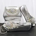 Elegantes Set aus silbernen Plateausandalen und Handtasche mit verzierten Strassblumen. - Silber
