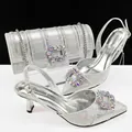 Silver pointed-toe pumps and matching cylinder clutch bag with rhinestone buckles - Silver