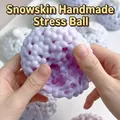 Gros plan de mains pressant une balle anti-stress violette à texture granuleuse - Avec Outil de Pompe à Air / Surdimensionné / Violet