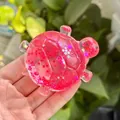 Detaillierte Makroansicht eines rosa Glitzer-Schildkröten-Squishy-Stressspielzeugs. - Schildkröte Stil / Rot